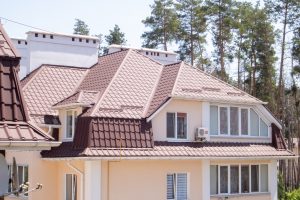 Roof on residential property with new brown corrugated metal roof tiles. Modern metal roof. 